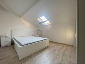 a white bedroom with a bed and a skylight at Mansarda vista mare in Imperia
