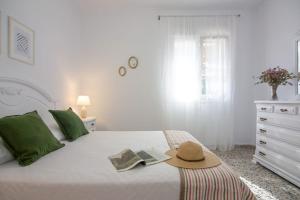 una camera bianca con un letto con un cappello sopra di CASA DE MECA, a 100m de la playa a Los Caños de Meca
