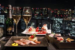 una mesa con dos copas de vino y comida en Shinagawa Prince Hotel, en Tokio
