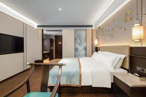 長沙市にあるTill Bright Hotel, Changsha Yanghu University of Traditional Chinese Medicineの大きなベッドとテーブルが備わるホテルルームです。