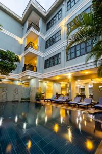 a hotel with a swimming pool in front of a building at Siem Reap Comforts Hostel in Siem Reap