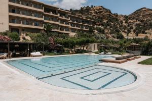 een zwembad met een hotel op de achtergrond bij The Maxine Hotel Adults Only in Agia Galini