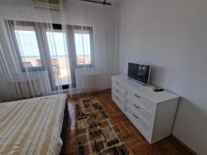 a bedroom with a bed and a dresser with a tv on it at Leon Apartment in Constanţa