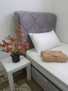 a bed with a pillow and a plant on a table at ER Homestay 2R1B suite nearby KLIA Terminal in Sepang