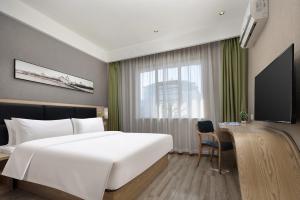 a bedroom with a large white bed and a television at Morninginn, Tidu Middle Road in Lengshuijiang