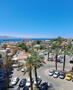 Un estacionamiento con autos estacionados y palmeras. en סוויטת הנופש שלי נגיעה מהים, en Eilat