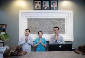 un gruppo di tre persone che pregano davanti a un computer portatile di Siem Reap Comforts Hostel a Siem Reap