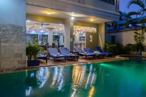 a swimming pool with blue lounge chairs next to a building at Siem Reap Comforts Hostel in Siem Reap