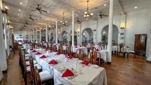 a large banquet hall with white tables and red napkins at Queen's Hotel in Kandy