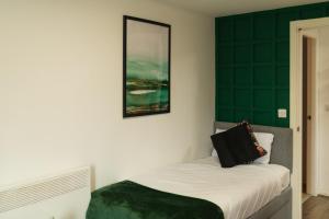 a bedroom with a bed and a green wall at Central Oasis, Serene Convenient 2-Bedroom Haven in L1 in Liverpool