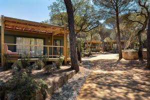 een geel huis met een bankje ervoor bij wecamp Santa Cristina in Santa Cristina d'Aro