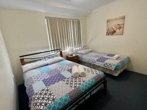 2 camas individuales en una habitación con ventana en Sunset on Swift, en Broadwater