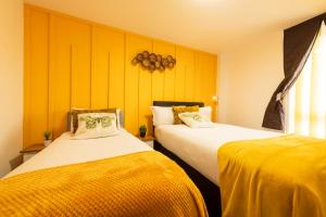 two beds in a room with yellow walls at Sidemersey Livings- Rare Accessible 2BR Liverpool City Centre Apartment in Liverpool