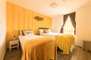 a bedroom with two beds with yellow sheets and a window at Central Oasis, Serene 2-Bedroom Haven in L1 Liverpool in Liverpool