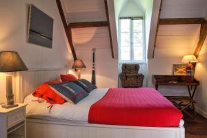 - une chambre avec un lit et une couverture rouge dans l'établissement Le Petit Manoir de Kériolet, à Concarneau