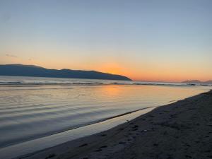 a beach with the sun setting over the water at Arlind's Apartaments in Vlorë