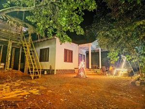 Eine Frau steht nachts vor einem Haus in der Unterkunft Wayanad Days in Mananthavady