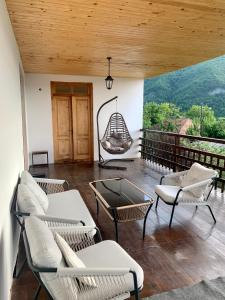 a porch with chairs and a hanging swing at Panorama ananuri guest house in Ananuri