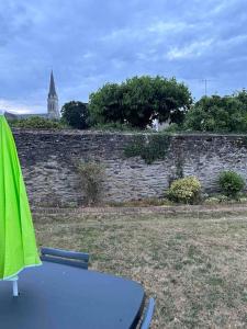 a table and chairs in front of a stone wall at Downtown cozy cottage - 4 pl - in Château-Gontier