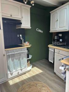 una cocina con armarios blancos y una pared verde en Downtown cozy cottage - 4 pl -, en Château-Gontier
