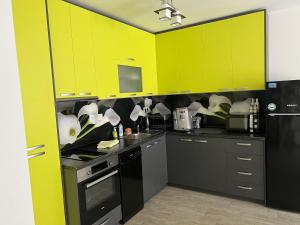 una cocina con armarios amarillos brillantes y electrodomésticos negros en Апартамент Трапезица en Veliko Tŭrnovo