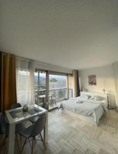 Schlafzimmer mit einem Bett und einem Tisch mit einem Schreibtisch in der Unterkunft Cannes Marina Résidence Le Surcouf - Studio de 28m2 au 10ème étage avec piscine, terrasse, parking, vue montagne et port : Mandelieu-La Napoule in Mandelieu-la-Napoule