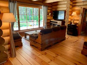 una sala de estar con sofá y TV en una cabaña de madera en Kasepuu Holiday House en Uulu