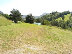 a large grassy field with a green tent in the distance at Les amandiers in Gigors
