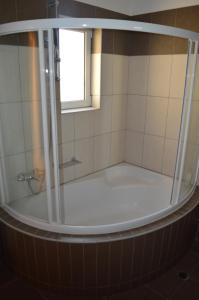 a bath tub with a shower and a window at VILLA AVATOS - Near to the port of Rafina and the airport of Athens in Áyios Spirídhon