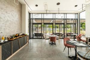 - une salle à manger avec des tables, des chaises et des fenêtres dans l'établissement Mirabilis Boutique Hotel by Panel Hospitality, à Kalambaka