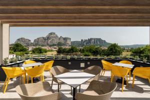 d'une terrasse avec des tables et des chaises et des montagnes en arrière-plan. dans l'établissement Mirabilis Boutique Hotel by Panel Hospitality, à Kalambaka