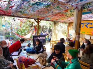 a group of people sitting around a table in a room at Kamagasaki University of the Arts Cafe Garden Guest House aka Cocoroom in Osaka