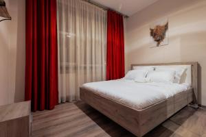 a bedroom with a large bed with red curtains at City Nest Maria Short Stay in Baia Mare