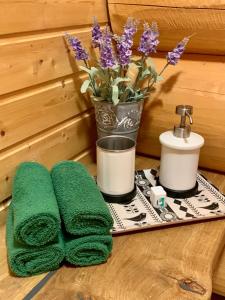 a tray with two green towels and a vase of flowers at Kasepuu Holiday House in Uulu