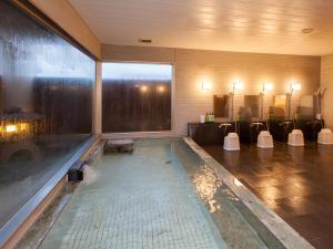 a swimming pool in a room with a large window at Business Hotel Isesaki Heisei Inn in Isesaki