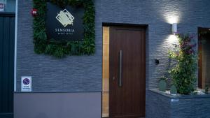 Sensoria Naxos Suites في جيارديني ناكسوس: علامة على جانب مبنى مع باب