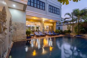 una piscina al centro di un edificio con sedie blu di Siem Reap Comforts Hostel a Siem Reap
