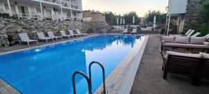 una gran piscina azul con sillas y mesas. en Hotel Nereides, en Patitiri