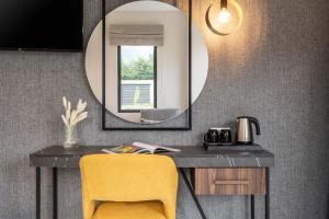 a mirror above a desk with a yellow chair at Mirabilis Boutique Hotel by Panel Hospitality in Kalabaka
