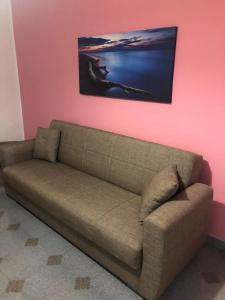 Sofá marrón en una habitación con pared rosa en Casa Vacanze #23, en SantʼAgata di Militello