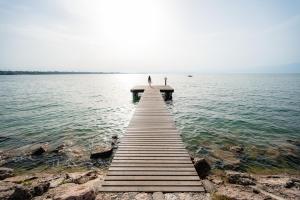 Glamping Lake Garda في بسكيرا ديل غاردا: شخص يقف على رصيف في الماء