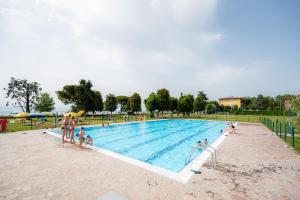 een groep mensen die rond een zwembad staan bij Glamping Lake Garda in Peschiera del Garda
