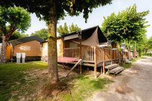 a tent with a table and a bench next to a tree at Glamping Lake Garda in Peschiera del Garda