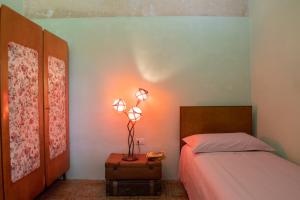 una camera con un letto e una lampada su una valigia di "A CASA COGONI - OSPITALITÀ e CULTURA" a Monserrato