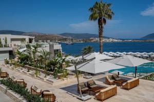 a hotel patio with chairs and umbrellas and the ocean at Mirada Exclusive Bodrum in Bodrum City