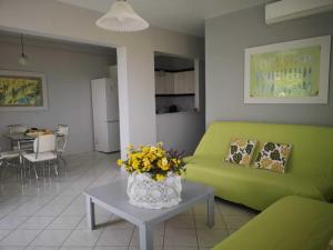 a living room with a green couch and a table with flowers at Apartments Jasu in Kivérion