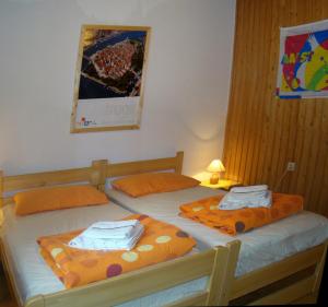 two twin beds in a room with orange pillows at Apartments Maroflin in Crni Lug +9 photos