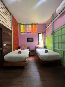 2 Betten in einem Zimmer mit farbenfrohen Wänden in der Unterkunft tamarind guesthouse in Phra Nakhon Si Ayutthaya