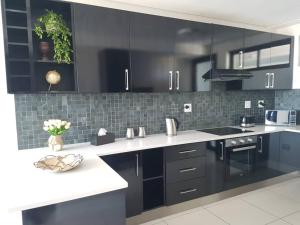 a kitchen with black cabinets and white counter tops at Movic's Modern Airbnb in Windhoek