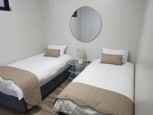 two beds in a room with a mirror at Movic's Modern Airbnb in Windhoek